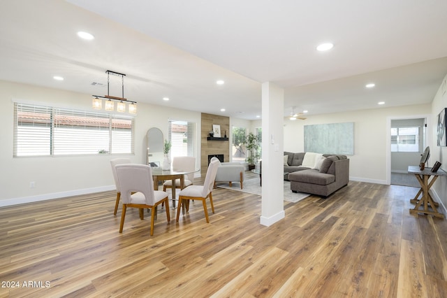 dining space with a tiled fireplace, a wealth of natural light, and wood-type flooring