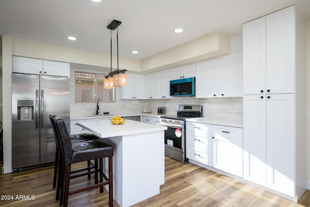 kitchen featuring white cabinetry, a center island, stainless steel appliances, light hardwood / wood-style flooring, and decorative light fixtures