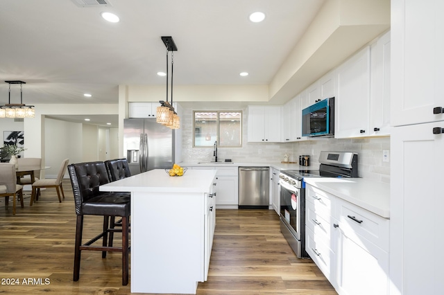 kitchen featuring appliances with stainless steel finishes, dark wood-type flooring, sink, white cabinets, and a center island