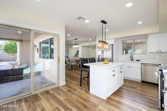 kitchen featuring a kitchen island, white cabinetry, stainless steel appliances, and light hardwood / wood-style flooring