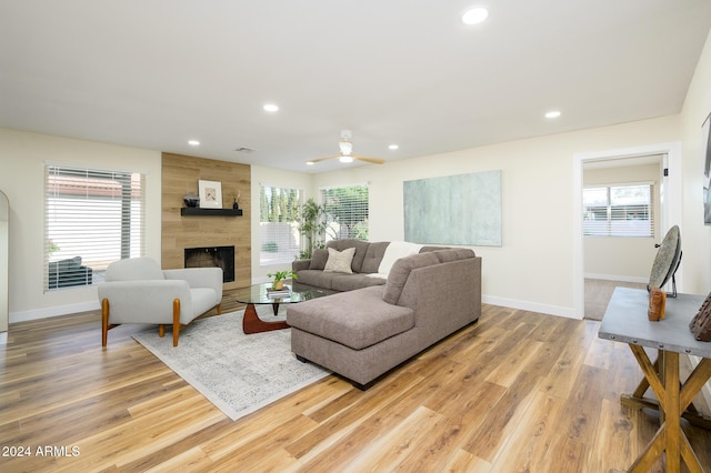 living room featuring a tile fireplace, a wealth of natural light, ceiling fan, and light hardwood / wood-style floors