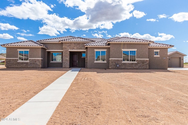 mediterranean / spanish home with a tile roof, stone siding, driveway, and stucco siding