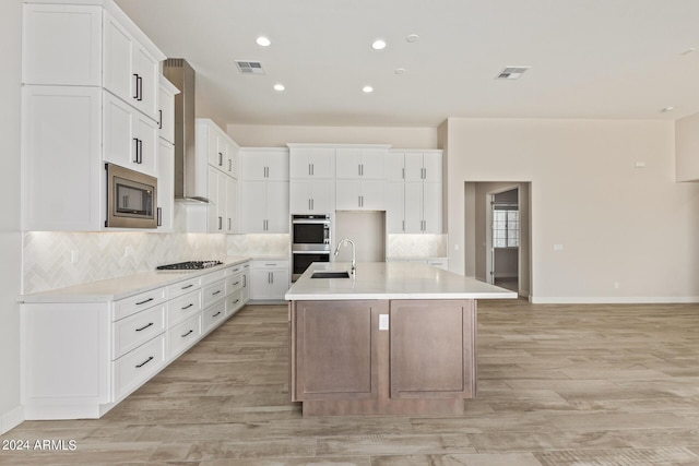 kitchen featuring sink, white cabinetry, a center island with sink, stainless steel appliances, and backsplash