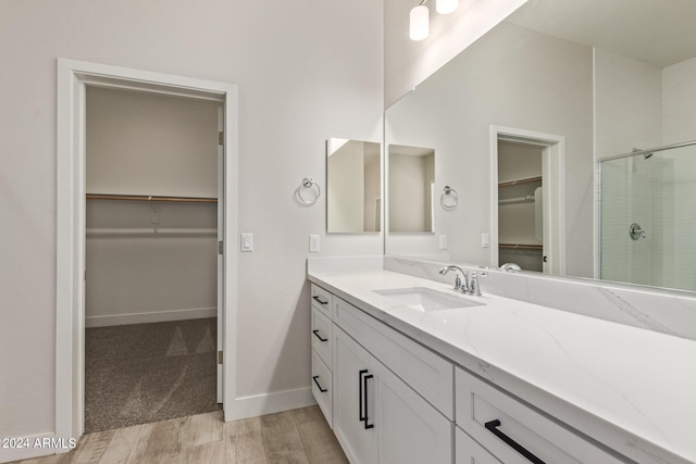 bathroom featuring vanity, a shower with shower door, and wood-type flooring