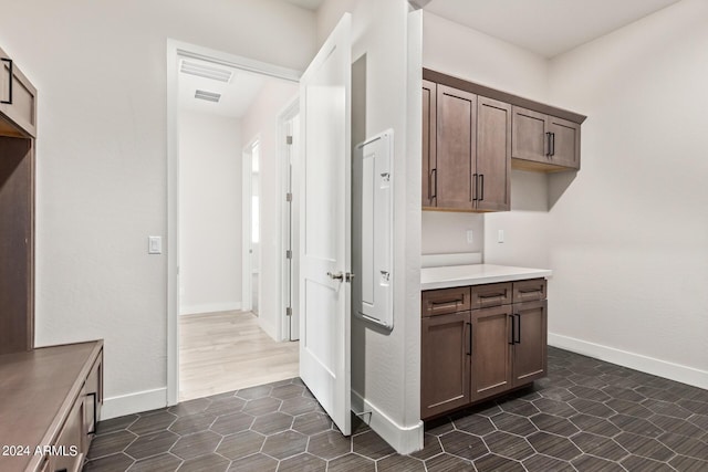 kitchen featuring dark tile patterned flooring and dark brown cabinets