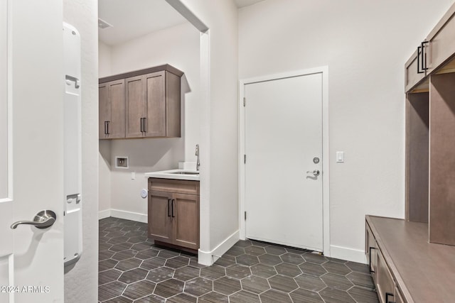 washroom with cabinets, sink, washer hookup, and dark tile patterned floors