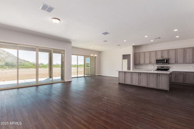 kitchen with dark hardwood / wood-style flooring, a mountain view, a notable chandelier, stainless steel appliances, and a kitchen island with sink