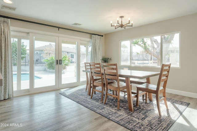 dining space with plenty of natural light, a chandelier, french doors, and light hardwood / wood-style flooring