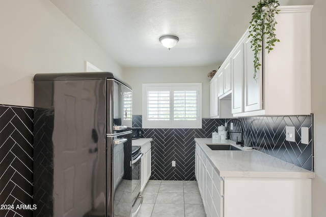 kitchen featuring light stone countertops, appliances with stainless steel finishes, sink, light tile patterned floors, and white cabinetry