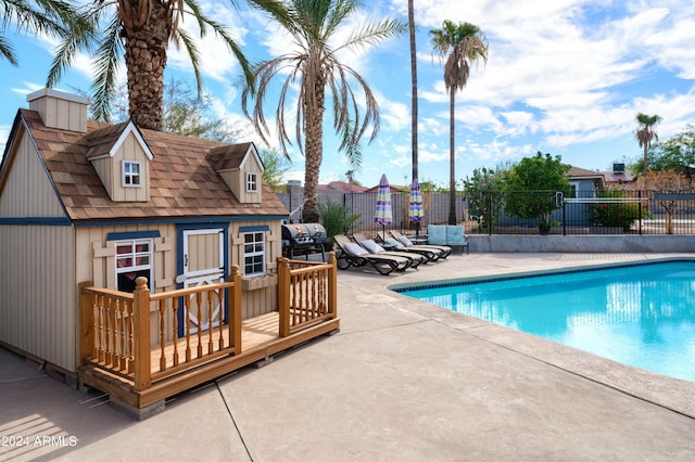 view of swimming pool with an outbuilding, a deck, and a patio area