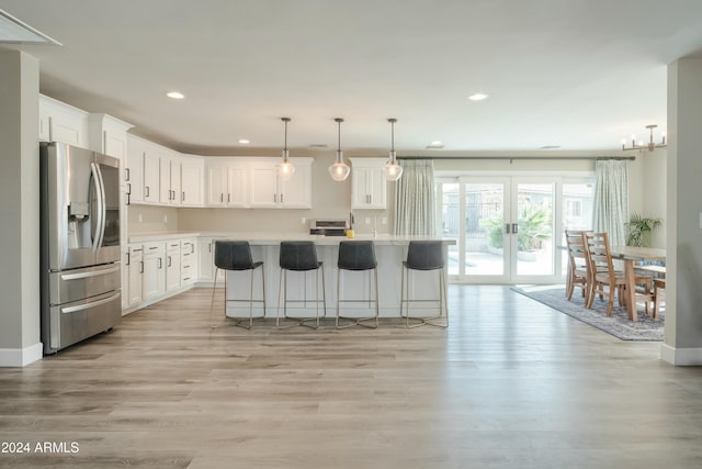 kitchen with white cabinetry, a center island, stainless steel refrigerator with ice dispenser, decorative light fixtures, and light wood-type flooring