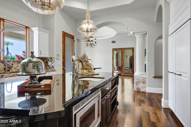 2527 E Beechnut Ct, Chandler, AZ 85249 - kitchen with a sink, decorative columns, stainless steel microwave, dark wood-style floors, and dark stone counters