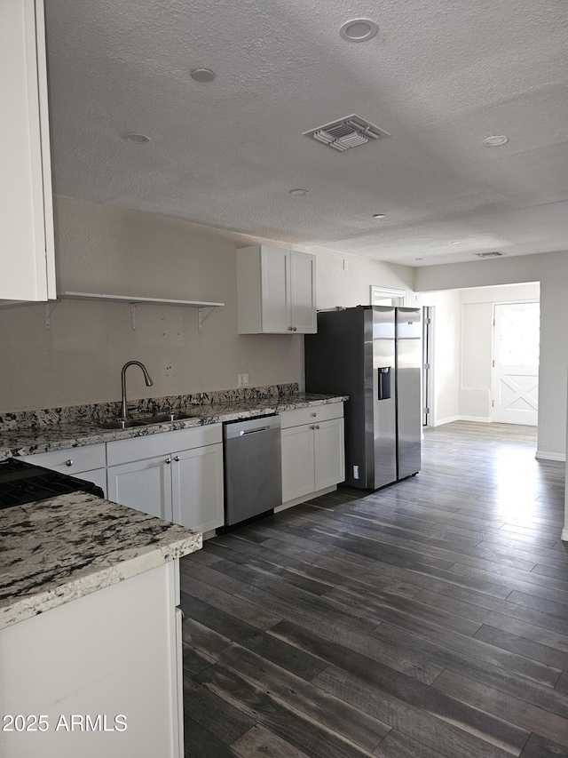 kitchen featuring dark wood-type flooring, sink, light stone counters, stainless steel appliances, and white cabinets