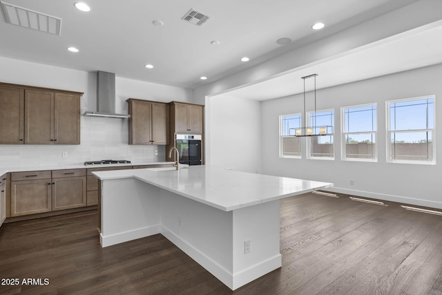 kitchen featuring stainless steel appliances, visible vents, a sink, and wall chimney range hood