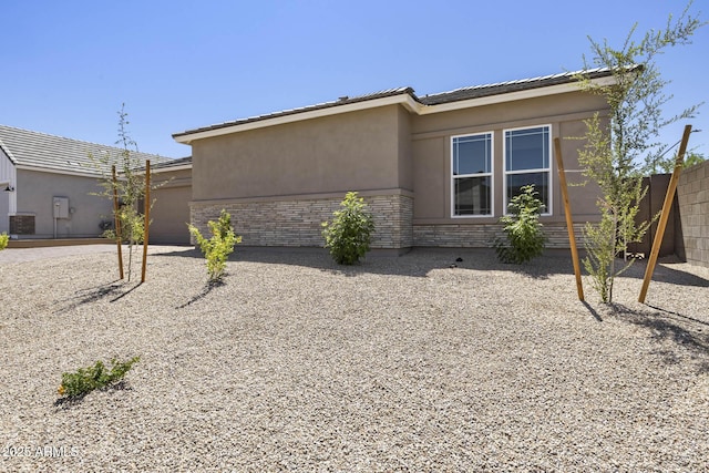 exterior space featuring a garage, stone siding, stucco siding, fence, and brick siding