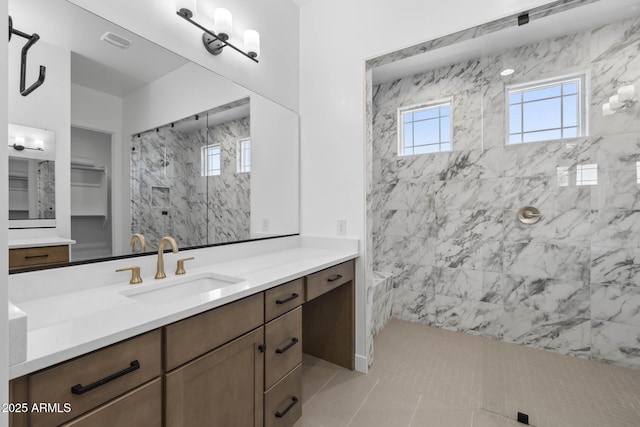 full bath featuring visible vents, tiled shower, and vanity