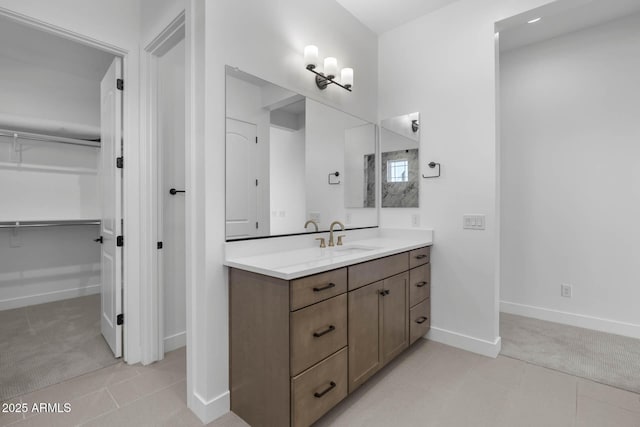 full bathroom featuring a walk in closet, tile patterned flooring, vanity, and baseboards