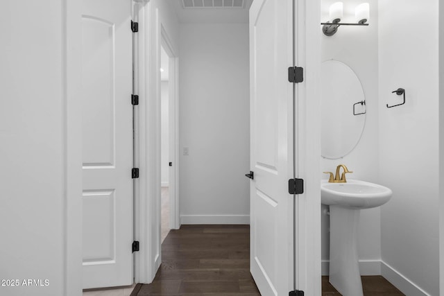 bathroom featuring a sink, visible vents, baseboards, and wood finished floors