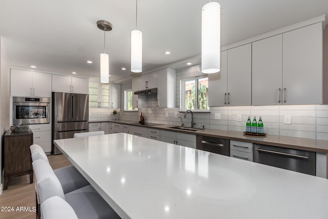 kitchen with pendant lighting, a kitchen breakfast bar, appliances with stainless steel finishes, and sink