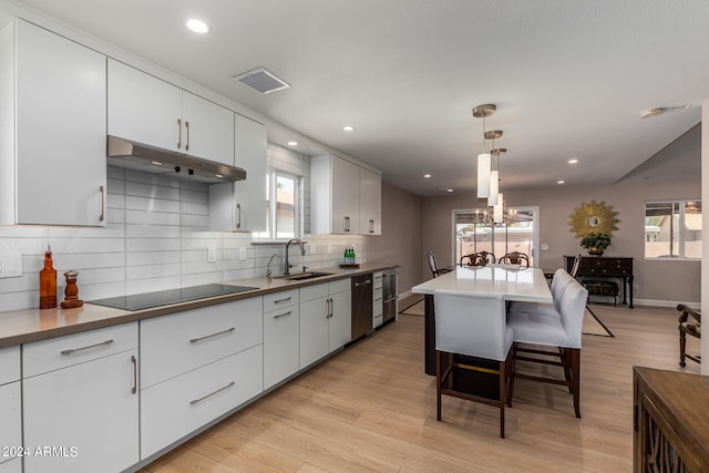 kitchen featuring black electric cooktop, decorative light fixtures, light wood-type flooring, and white cabinetry