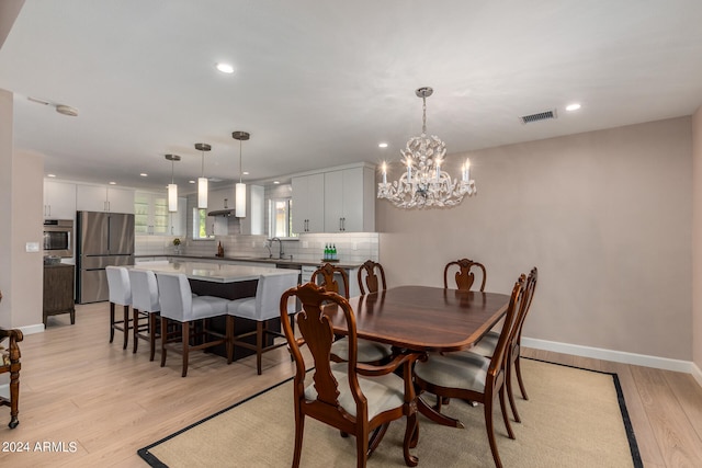 dining space featuring light hardwood / wood-style floors, sink, and a chandelier