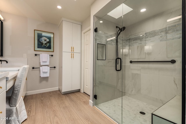 bathroom with vanity, hardwood / wood-style floors, a skylight, and a shower with door