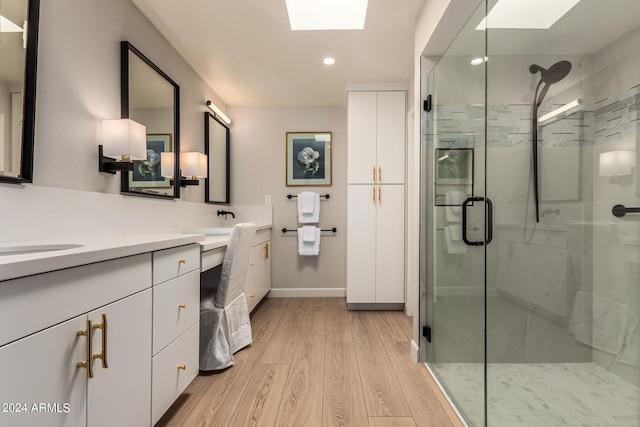 bathroom featuring a skylight, vanity, a shower with shower door, and hardwood / wood-style floors