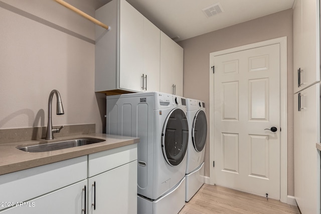 laundry room with washer and clothes dryer, cabinets, light hardwood / wood-style floors, and sink