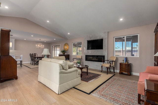 living room featuring light hardwood / wood-style floors, plenty of natural light, a chandelier, and a large fireplace