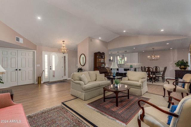 living room featuring light hardwood / wood-style floors, lofted ceiling, and a chandelier