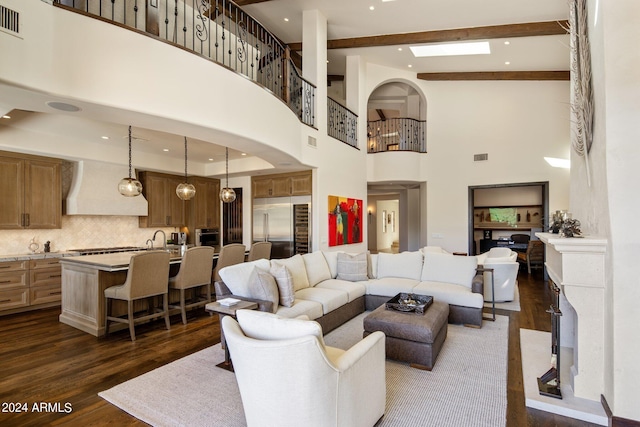 living room with beam ceiling, sink, a towering ceiling, and dark wood-type flooring