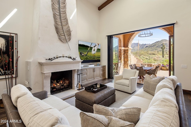 living room featuring a fireplace, a towering ceiling, beamed ceiling, and light wood-type flooring