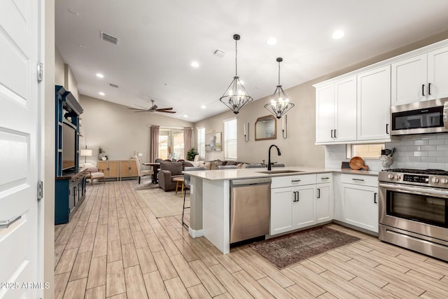 9624 E Thunderbolt Ave, Mesa, AZ 85212 - kitchen with appliances with stainless steel finishes, open floor plan, a peninsula, white cabinets, and lofted ceiling