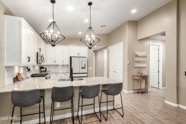 9624 E Thunderbolt Ave, Mesa, AZ 85212 - kitchen with stainless steel microwave, freestanding refrigerator, a peninsula, backsplash, and a chandelier