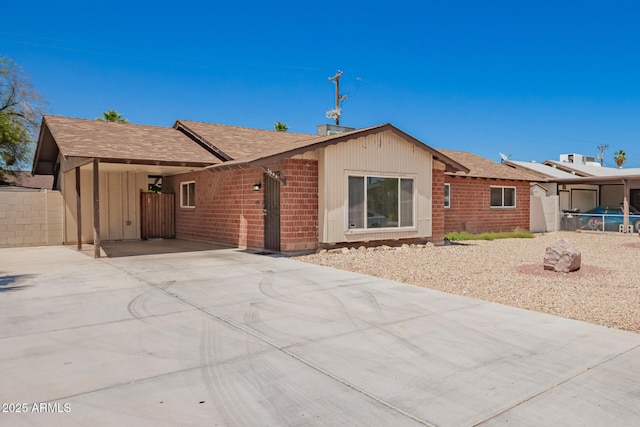 3644 W Maryland Ave, Phoenix, AZ 85019 - rear view of property featuring driveway, brick siding, roof with shingles, and a carport