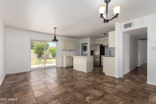 3644 W Maryland Ave, Phoenix, AZ 85019 - kitchen with stacked washing machine and dryer, stainless steel fridge, a kitchen island, light countertops, and baseboards