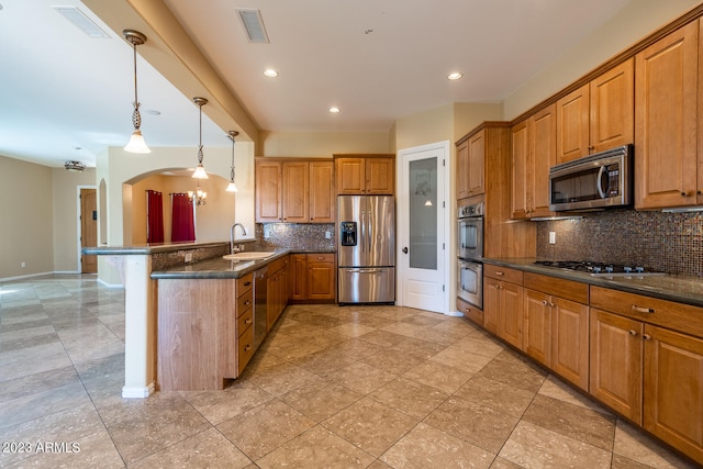 kitchen featuring stainless steel appliances, backsplash, light tile floors, decorative light fixtures, and sink