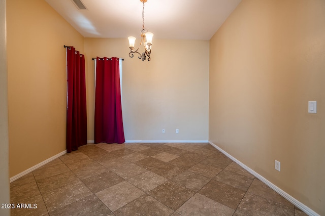 empty room with dark tile floors and an inviting chandelier