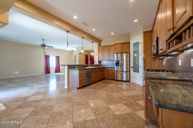 kitchen with ceiling fan, hanging light fixtures, backsplash, and stainless steel appliances