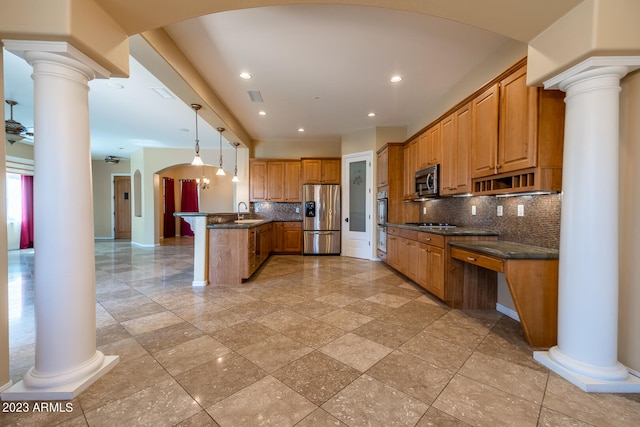 kitchen with decorative light fixtures, appliances with stainless steel finishes, ornate columns, backsplash, and sink