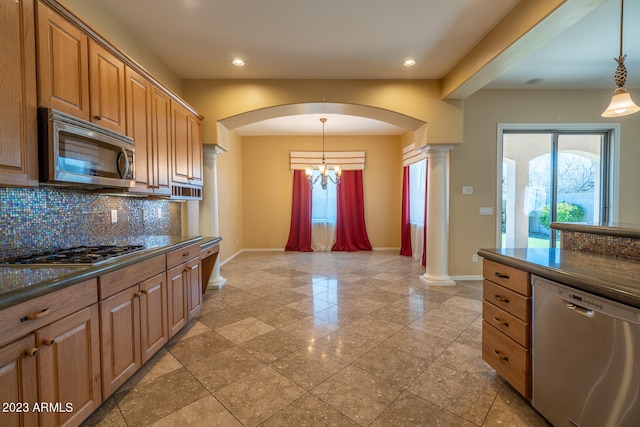 kitchen featuring decorative light fixtures, an inviting chandelier, appliances with stainless steel finishes, tasteful backsplash, and decorative columns