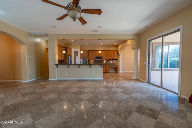 unfurnished living room featuring ornate columns, tile floors, and ceiling fan