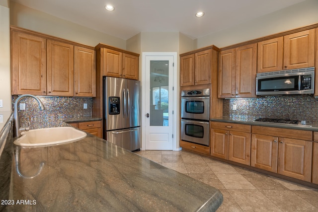 kitchen featuring light tile flooring, backsplash, appliances with stainless steel finishes, and sink