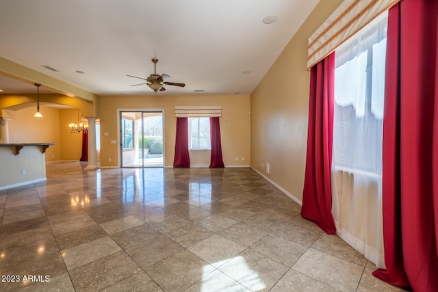 tiled spare room featuring ceiling fan with notable chandelier