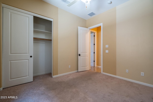 unfurnished bedroom featuring a closet, light colored carpet, and ceiling fan