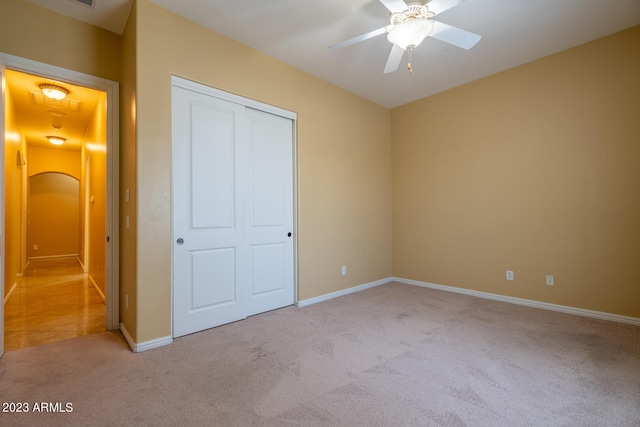 unfurnished bedroom featuring light colored carpet, a closet, and ceiling fan