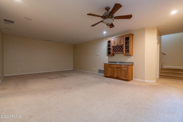 unfurnished living room featuring ceiling fan, sink, and light carpet