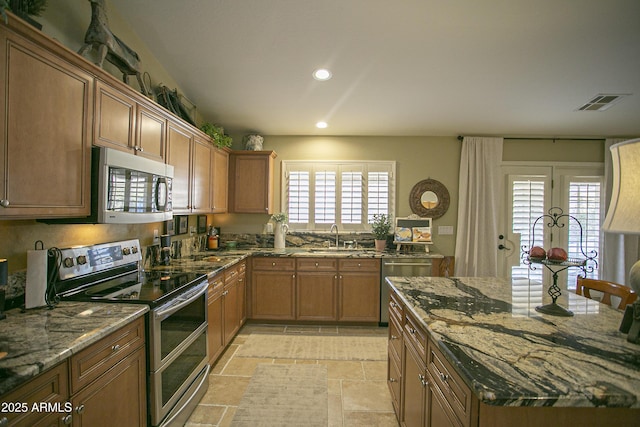 kitchen with sink, stainless steel appliances, and dark stone countertops