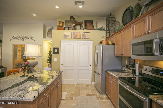 kitchen with light stone counters, stainless steel appliances, and a kitchen island