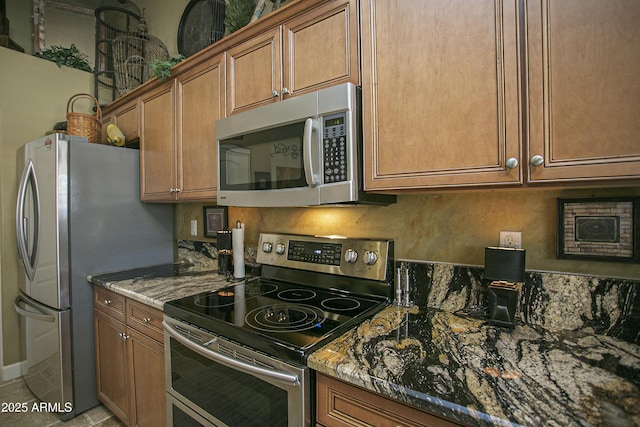 kitchen featuring light tile patterned floors, backsplash, appliances with stainless steel finishes, and dark stone countertops